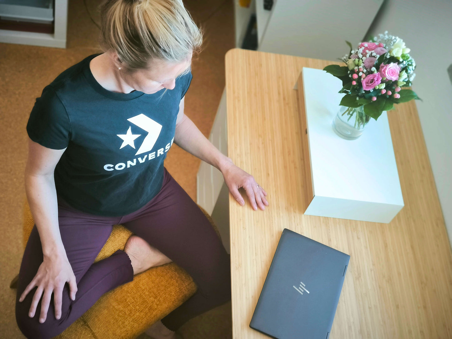 Frau sitzt am Schreibtisch auf gelbem Stuhl für den Schneidersitz