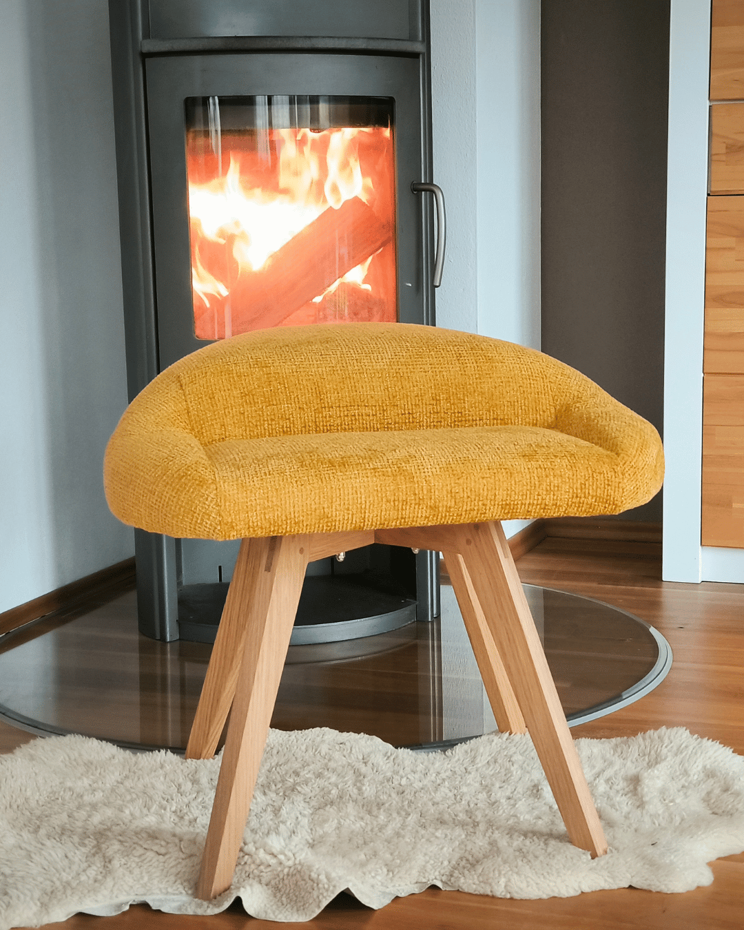 Bürostuhl für den Schneidersitz in gelb und Eiche, abgebildet drinnen vor einem Kamin