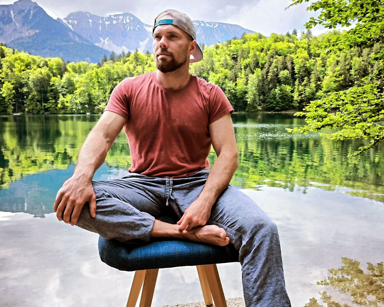 Gründer Lukas Richter sitzt auf Schneidersitz-Stuhl. Aufgenommen vor Bergsee.