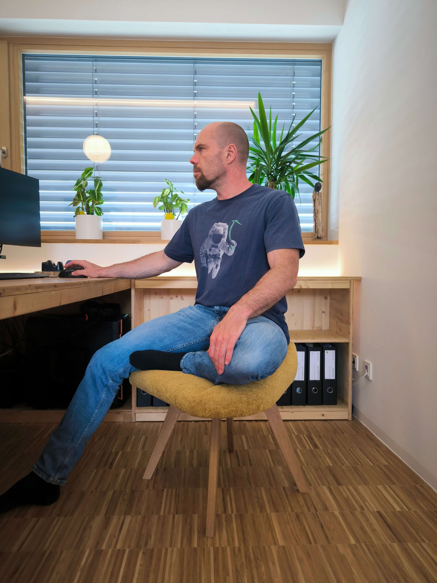 Mann sitzt im halben Schneidersitz auf dem Bürostuhl für den Schneidersitz